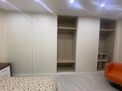 a bedroom with white cabinets and a bed and an orange chair at La casa de las Flores in Ponferrada