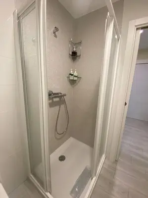 a shower with a glass door in a bathroom at La casa de las Flores in Ponferrada