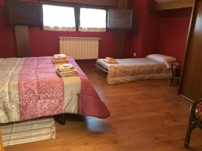 two beds in a room with red walls and wooden floors at Tía María in Cerredo