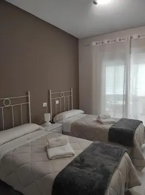 a room with three beds and a window at Pensión NAVIA A Pontenova in A Pontenova