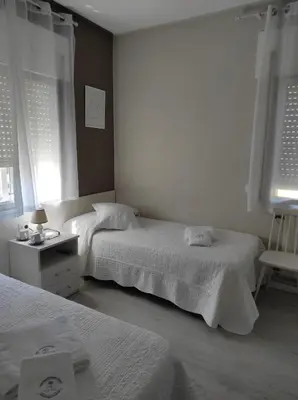 a bedroom with two beds and a table with a chair at Pensión NAVIA A Pontenova in A Pontenova
