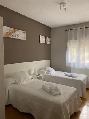 a bedroom with two beds and a window at Pensión NAVIA A Pontenova in A Pontenova