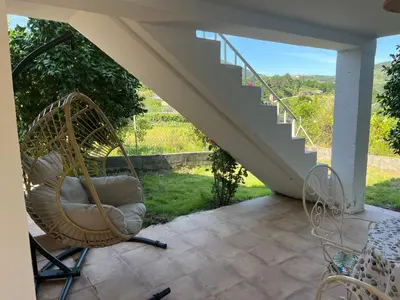 a wicker rocking chair on a patio with a staircase at Casa Catalina - Ribeira Sacra in Abeleda