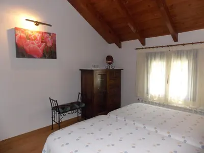 a bedroom with a bed and a chair and a window at Hostal El Recanto in Vega de Valcarce