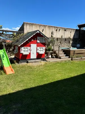 a small red house in a yard with a slide at Aturuxo, Casa dos Mestres in Trasmiras
