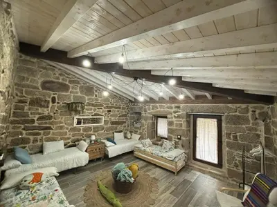 a living room with two couches and a stone wall at Aturuxo, Casa dos Mestres in Trasmiras