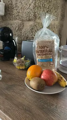 a plate of fruit on a table with a bag of food at Aturuxo, Casa dos Mestres in Trasmiras