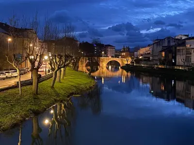 a river in a city at night with a bridge at Casa Vilachá - Ribeira Sacra in Puebla del Brollón
