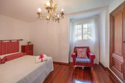 a bedroom with a bed and a chandelier and a chair at YourHouse A Casa Dos Cregos in Fonteita
