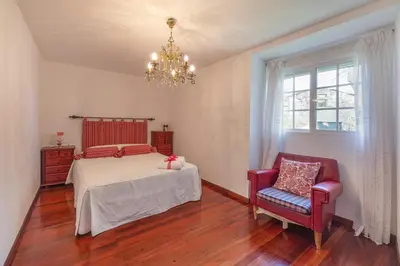 a bedroom with a bed and a chair and a chandelier at YourHouse A Casa Dos Cregos in Fonteita