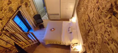 a room with a white bed and a stone wall at la solana del abuelo Andrés in La Chana