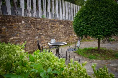 a table and chairs in front of a brick wall at Casas Rurales Taramundi Verde in Taramundi