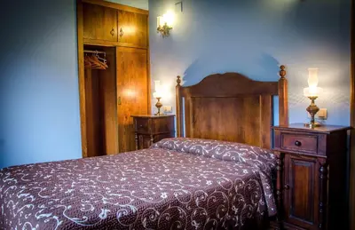 a bedroom with a bed and two lights on the wall at Casas Rurales Taramundi Verde in Taramundi