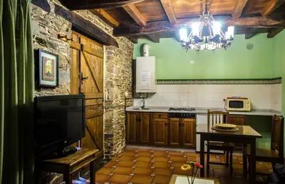 a kitchen with a table and a chandelier in a room at Casas Rurales Taramundi Verde in Taramundi