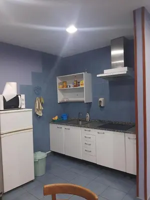 a kitchen with white cabinets and a blue wall at Albergue Berce do Camiño in Tríacastela