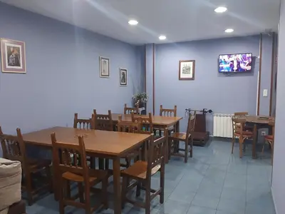 a dining room with tables and chairs and a tv at Albergue Berce do Camiño in Tríacastela