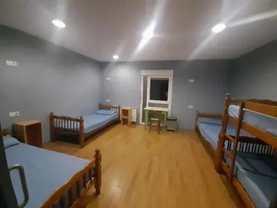 a room with three bunk beds and a table at Albergue Berce do Camiño in Tríacastela