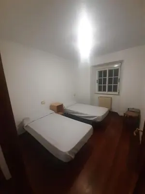 two beds in a room with wooden floors and a window at Albergue Berce do Camiño in Tríacastela