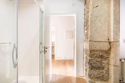 a glass shower in a bathroom with a stone wall at Casa Taboada in San Román