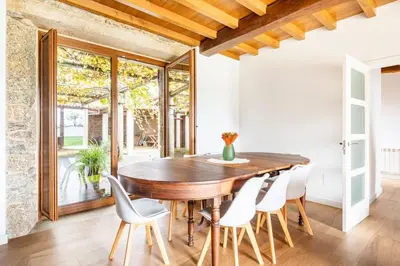 a dining room with a wooden table and white chairs at Casa Taboada in San Román