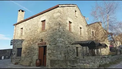 an old stone building with an umbrella in front of it at Venta Celta in O Cebreiro