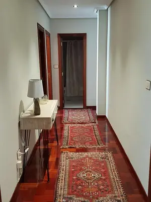 a hallway with a table and two rugs on the floor at El Descanso de Ana in Ourense