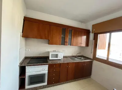 a kitchen with wooden cabinets and a white microwave at Pension Matias Rooms in Sarria