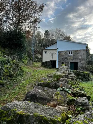 a stone building in a field with some rocks at Sola Costeiro in Padrenda