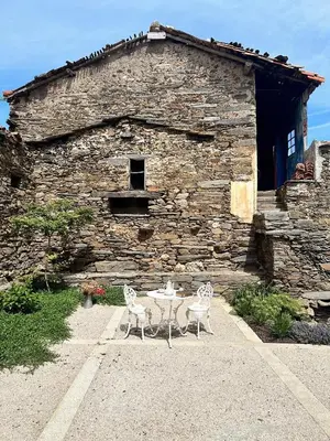 two chairs and a table in front of a stone building at Casa Dona Ildara in Doade