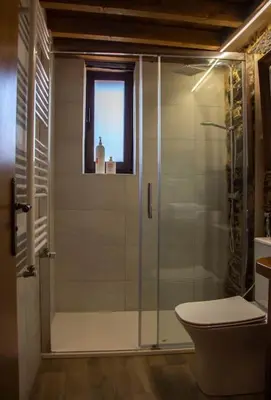 a bathroom with a shower with a toilet and a window at Casa Dona Ildara in Doade