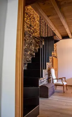 a staircase in a room with a chair and a table at Casa Dona Ildara in Doade