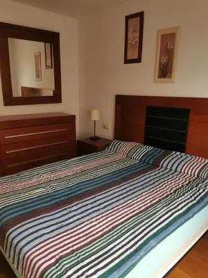 a bed with a striped comforter in a bedroom at ALE HOSPEDAJE GALICIA in Temple