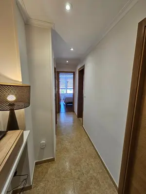 a hallway with a white wall and a room with a couch at Los Castelos by Urraca Suites Viveiro in Viveiro