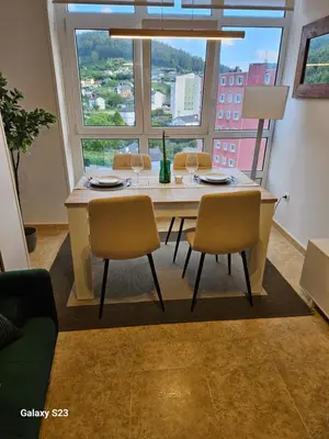 a dining room table with chairs and a large window at Los Castelos by Urraca Suites Viveiro in Viveiro