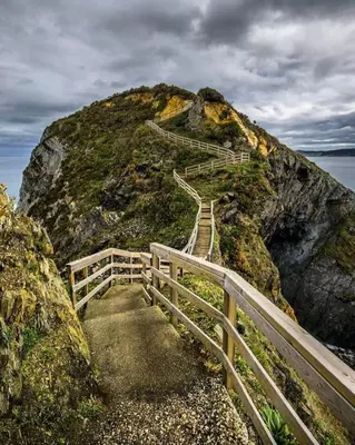 a stairway leading up to a hill with a wooden fence at Los Castelos by Urraca Suites Viveiro in Viveiro
