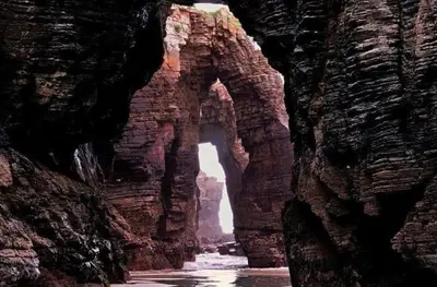 an archway in a rock formation in the water at Los Castelos by Urraca Suites Viveiro in Viveiro
