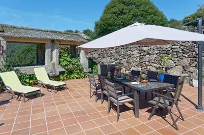 a patio with a table and an umbrella at Casa Del Ingles - Luxury Private Villa & Pool in Rural Valley in Pontevedra