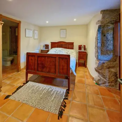 a bedroom with a bed and a stone wall at Casa Del Ingles - Luxury Private Villa & Pool in Rural Valley in Pontevedra