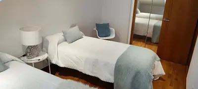 a small bedroom with two beds and a mirror at Apartamento Buen Camino in O Pedrouzo