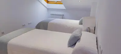 two beds in a white room with a window at Apartamento Buen Camino in O Pedrouzo