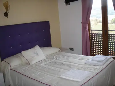 a bedroom with a bed with a blue headboard and a window at Hostal la Cuesta in Vega de Espinareda