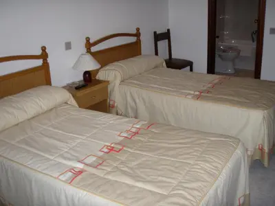 a hotel room with three beds with white sheets at Hostal la Cuesta in Vega de Espinareda