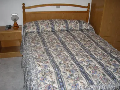 a bed with a quilt on it in a bedroom at Hostal la Cuesta in Vega de Espinareda