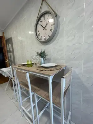 a table with chairs and a clock on a wall at Appartement vistahermosa in Vivero