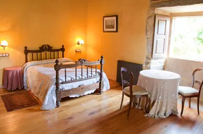 a bedroom with a bed and a table and chairs at Pazo de Andeade in Andeade