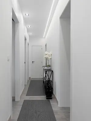 a hallway with white walls and a table with flowers on it at El Rincón de la estación in Ourense