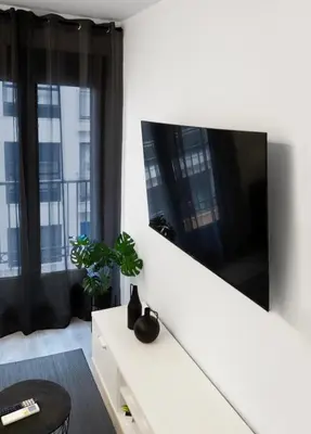 a white living room with a large tv on a wall at El Rincón de la estación in Ourense