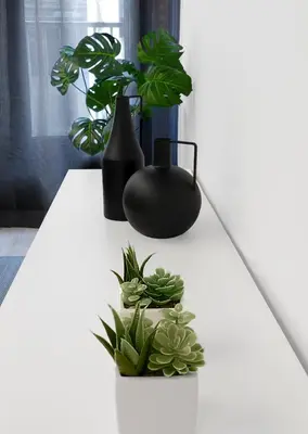 a white table with two plants and a black vase at El Rincón de la estación in Ourense