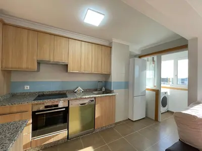 a kitchen with wooden cabinets and a stainless steel refrigerator at APARTAMENTO NUEVO EN BURELA - A Mariña, Galicia in Burela de Cabo