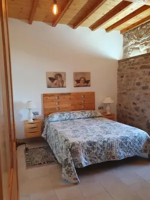 a bedroom with a bed and a stone wall at Casa Rural El Bierzo Oro en el Camino in Villaverde de la Abadía